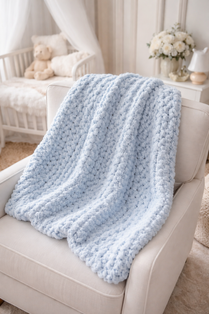 Light blue textured blanket draped over a white armchair in a cozy living room.